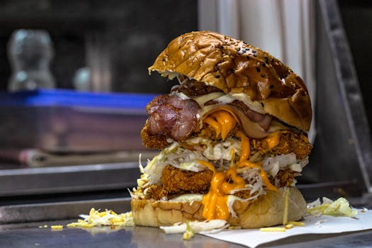 Close-up of a mouthwatering cheeseburger with bacon, cheese, and fried chicken patties.