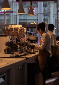 Barista crafting espresso in a modern café with warm lighting and professional equipment.