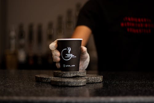 A Person Holding Brown and White Disposable Cup