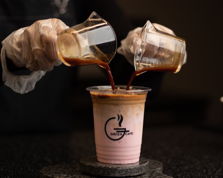 Person Pouring Coffee On Plastic Cup 