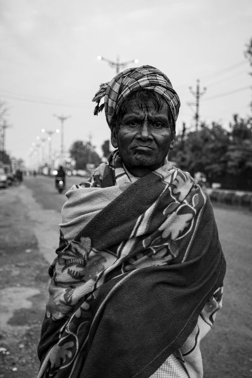 Free Black and white portrait of an elderly man standing on a street in India, wrapped in a patterned shawl. Stock Photo