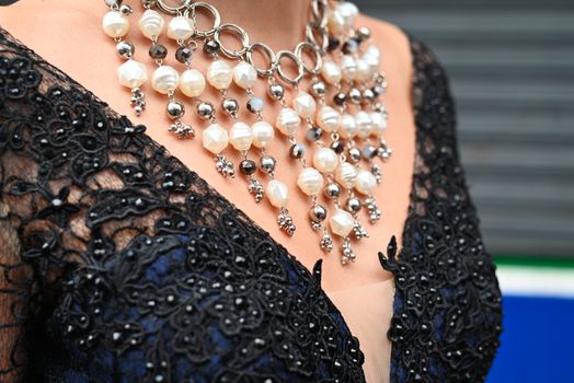 Detailed shot of an intricate pearl necklace on a black lace dress for fashion and accessory focus.