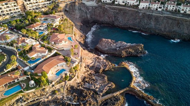 Stunning aerial view of luxury villas near the rocky shore of Santiago del Teide, Spain.