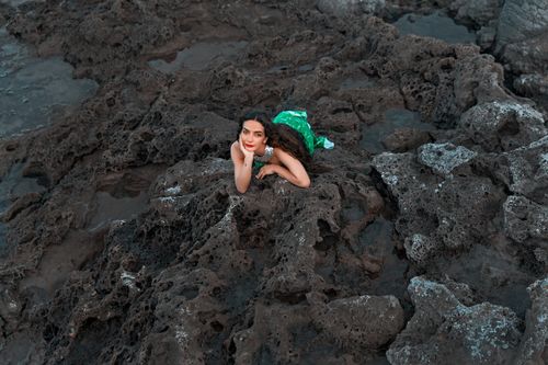 Free Aerial view of a woman in a green dress on rugged rocks in Istanbul, Turkey. Stock Photo