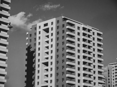 Black and white image of a modern high-rise building with balconies under a clear sky.