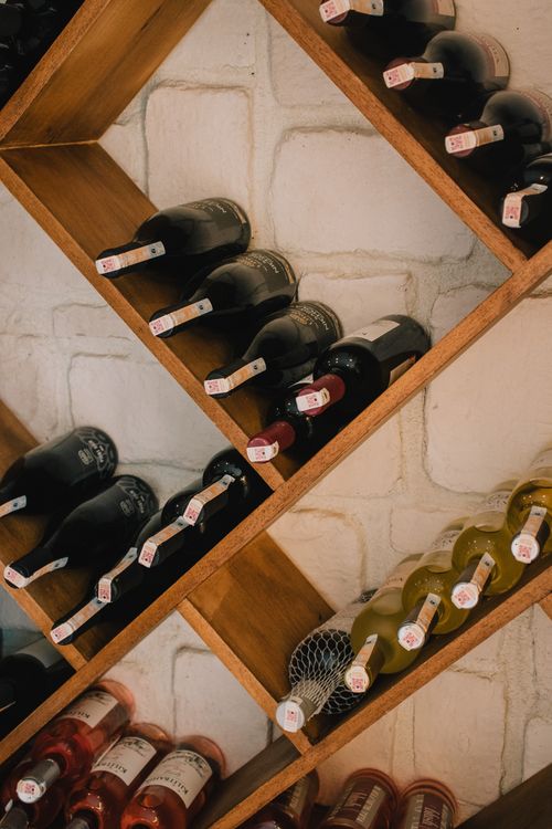 Free Stylish diagonal wine storage showcasing red, white, and rose wines in a cozy indoor setting. Stock Photo
