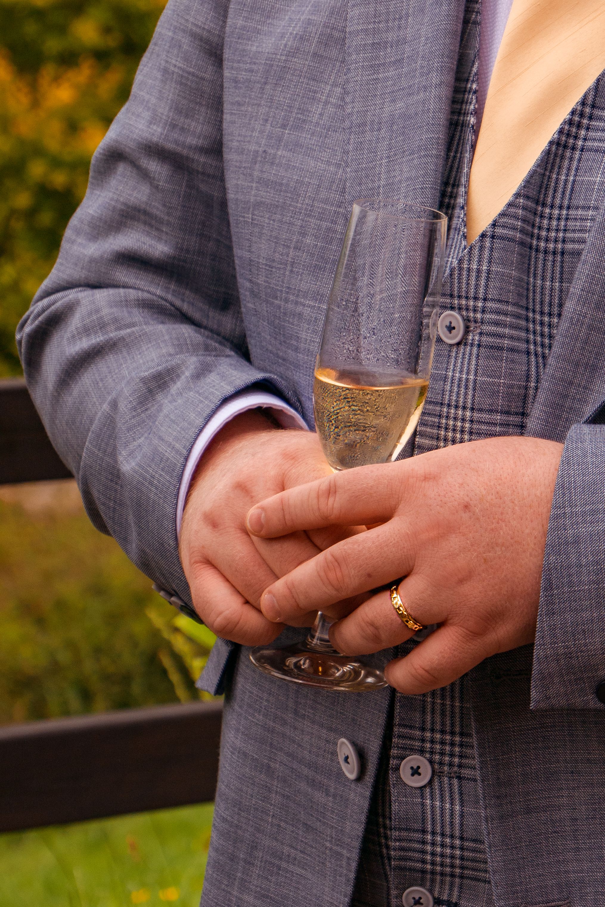 Elegant close-up of hands holding a champagne glass, wearing a suit. Ideal for celebrations or formal events.