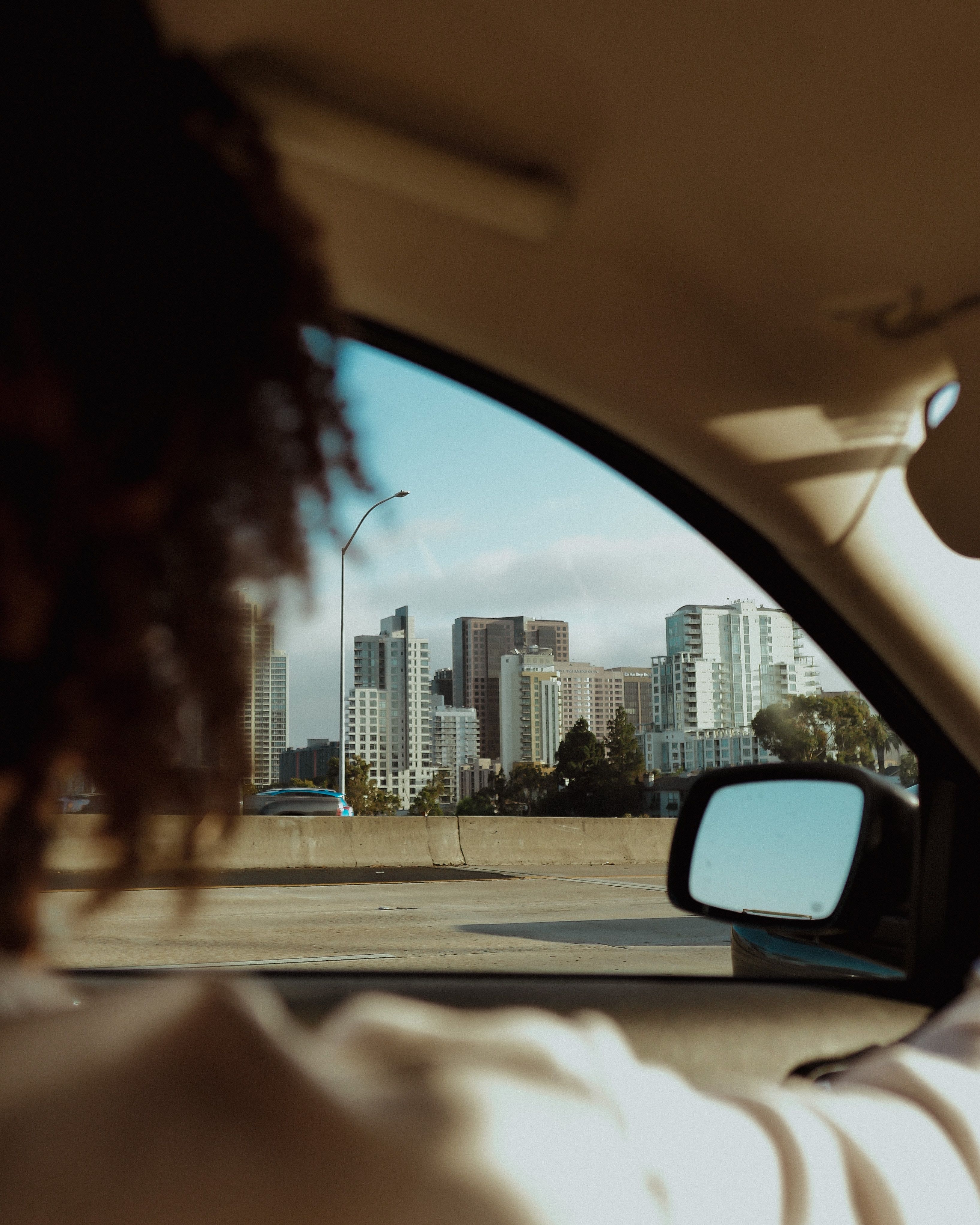 View of a city skyline through a car window with blurred figure in foreground.