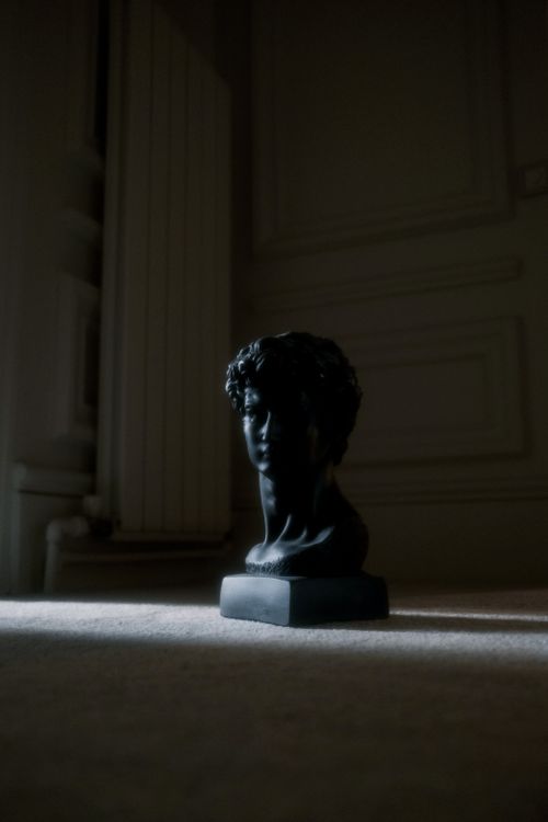 Free Stylized black sculpture bust in dramatic light and shadow, offering ample copy space. Stock Photo
