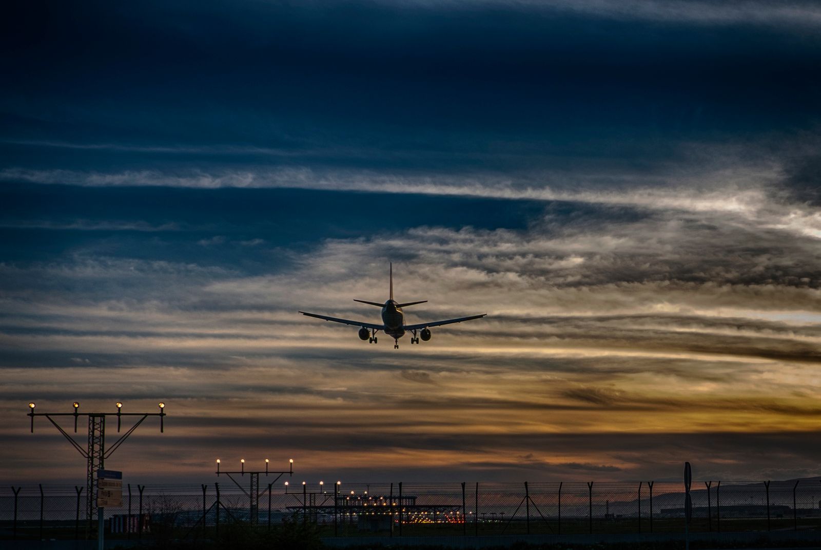 A passenger jet on final approach against a dusk sky, runway lights below