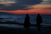 Silhouette of Couple Walking on Beach During Sunset