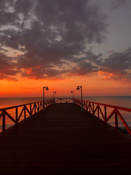 Free Vibrant sunset view over a pier in Katerini, Greece with dramatic skies. Stock Photo