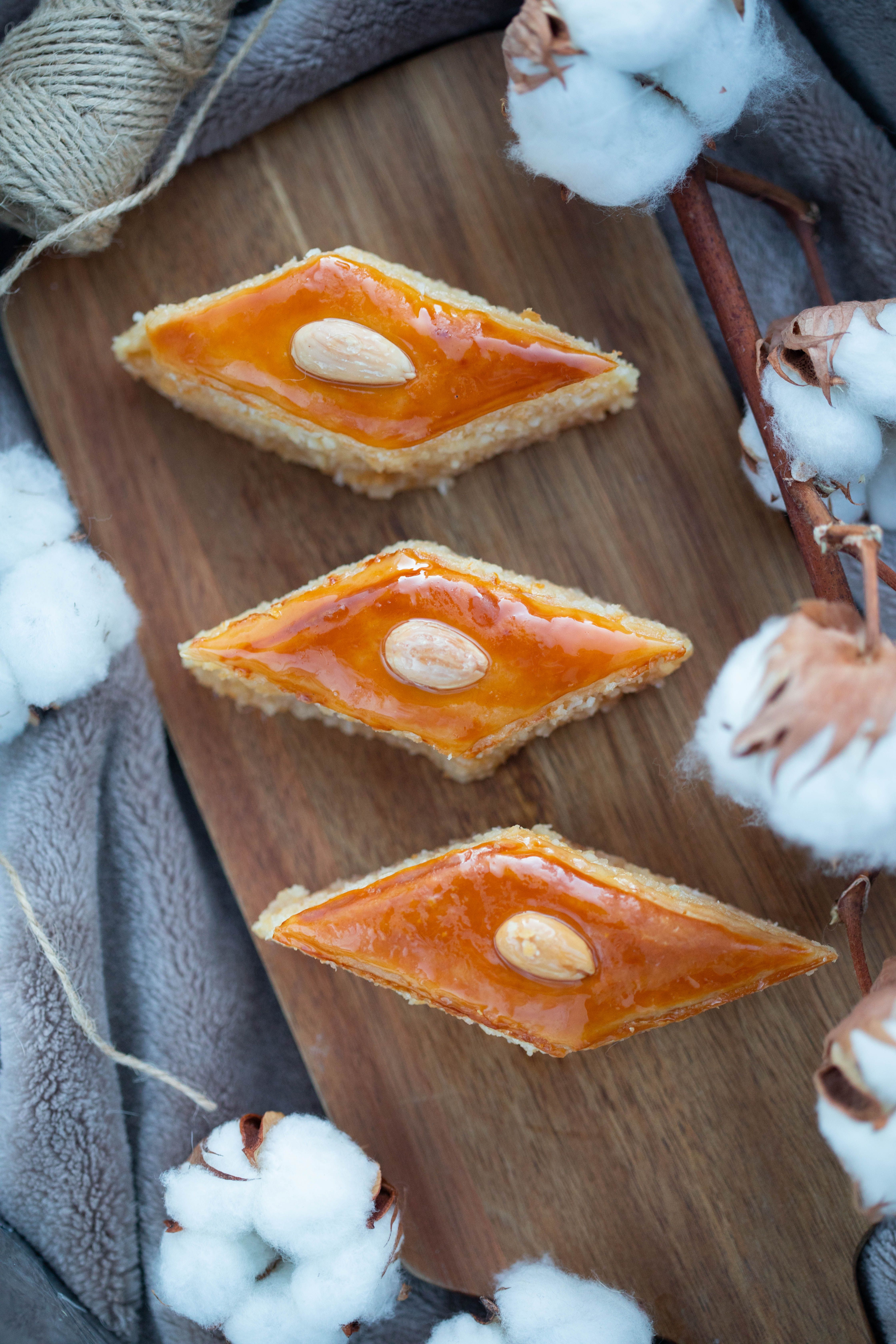 Artistic display of orange almond pastries on a rustic wooden board surrounded by cotton accents.