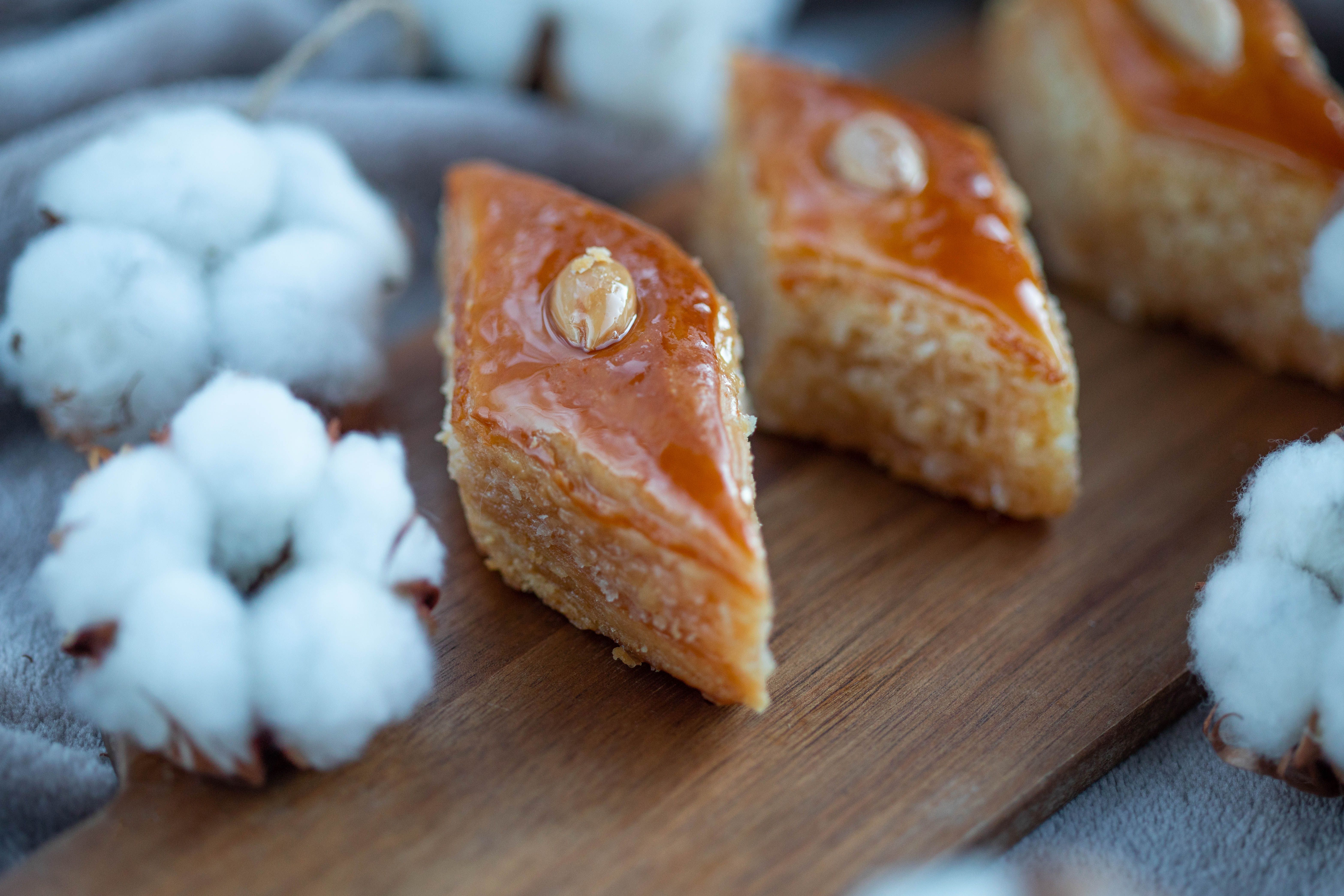 Close-up of delicious baklava slices on a wooden surface, adorned with cotton flowers, highlighting traditional desserts.