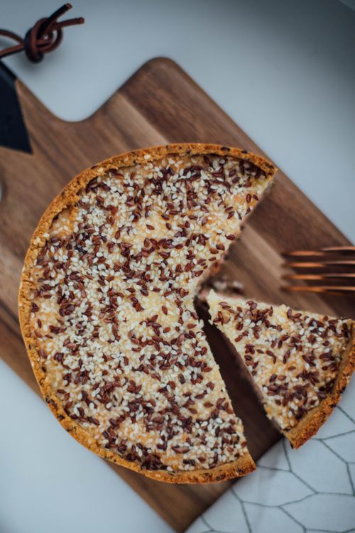Free Close-up of a savory pie sprinkled with seeds on a wooden board, shot from above. Stock Photo