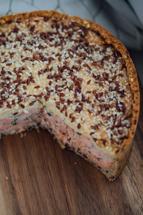 Free Close-up of a savory pie topped with sesame and flax seeds on a wooden board. Stock Photo