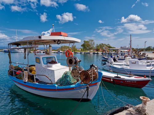 Free Colorful fishing boats docked at a Greek harbor under a clear blue sky. Stock Photo