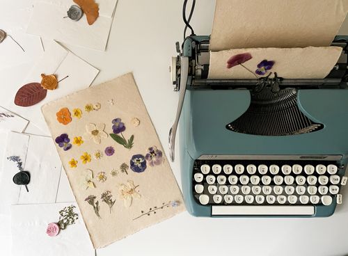 Free A vintage typewriter with pressed flowers on artisanal paper evokes nostalgia and creativity. Stock Photo