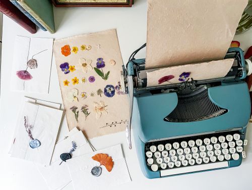 Free A charming scene of a vintage typewriter surrounded by floral-decorated envelopes and papers. Stock Photo