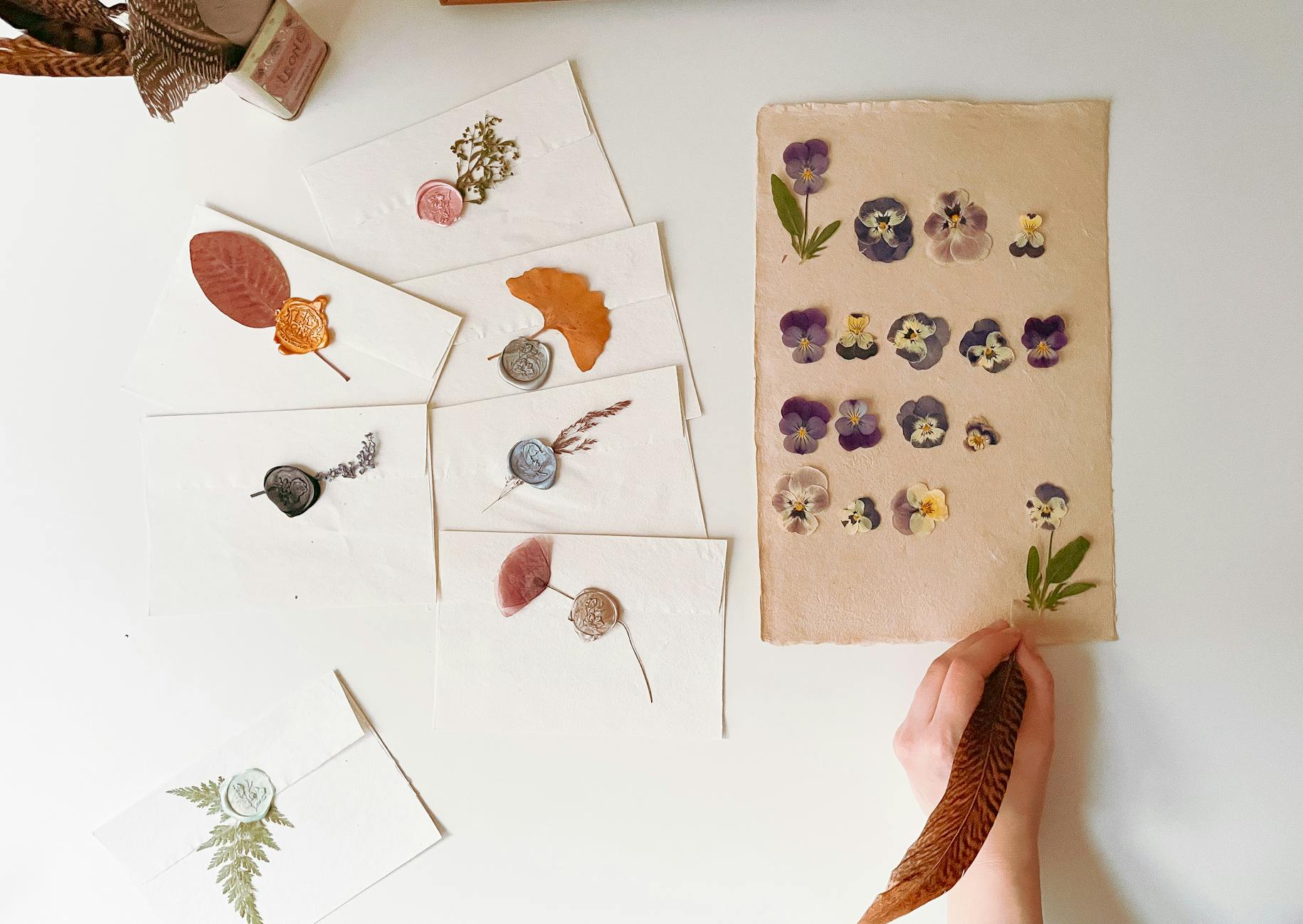 Beautiful flat lay featuring handmade envelopes with seals and dried flowers on a white background.