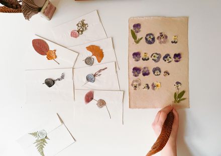 Pressed pansies on handmade paper beside wax-sealed envelopes — photo by Nur Yilmaz on Pexels