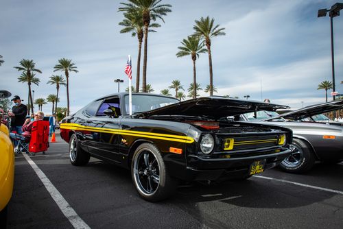 Free Vintage cars displayed under palm trees at an outdoor car show with people browsing. Stock Photo