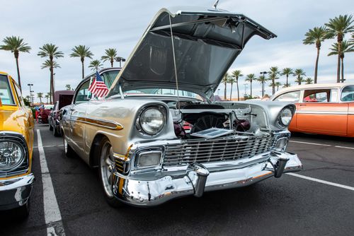 Free A classic vintage car with an open hood displayed at an outdoor car show with palm trees. Stock Photo