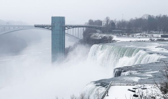 A breathtaking winter view of Niagara Falls with a bridge and snowy surroundings.