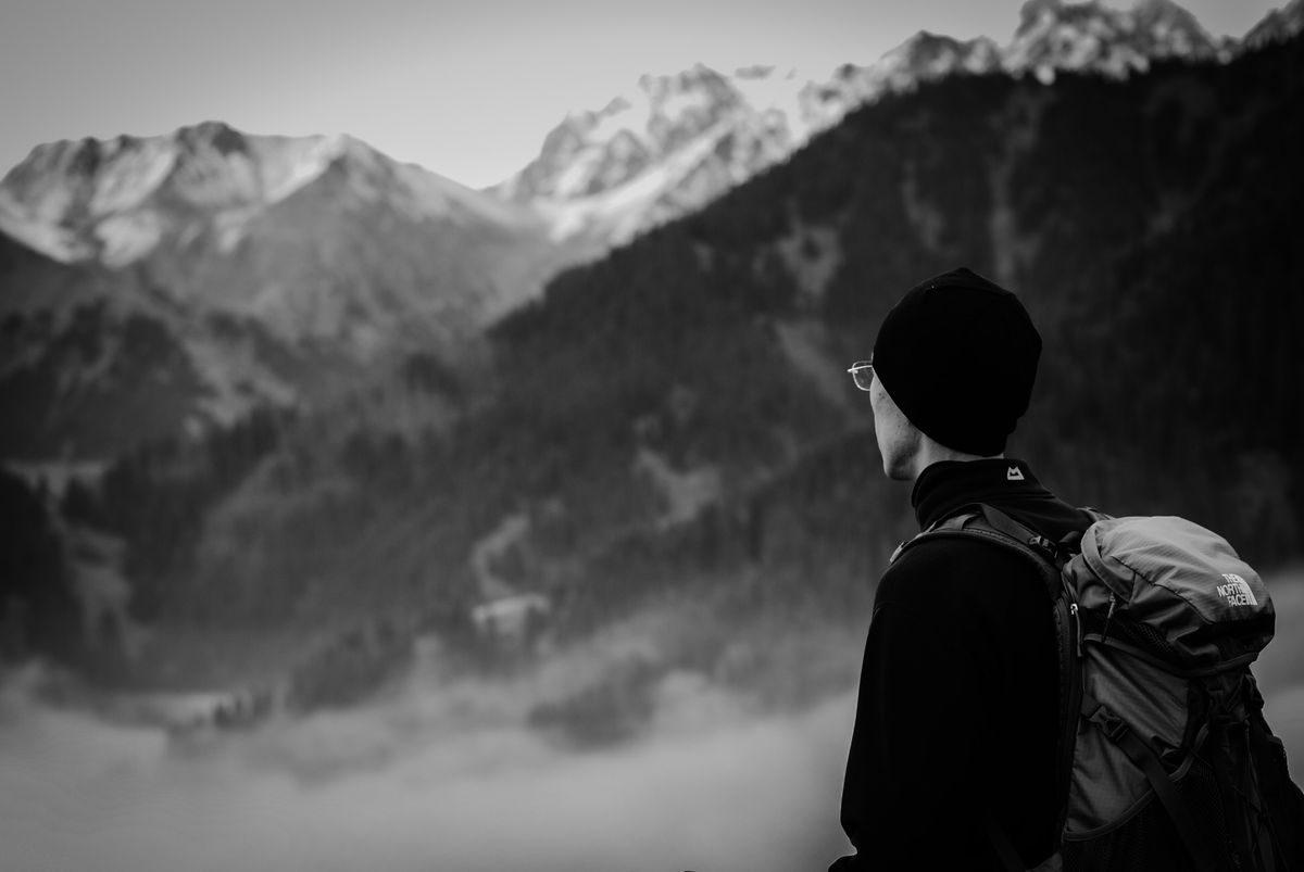 A man in a hat looking out over distant mountain ranges