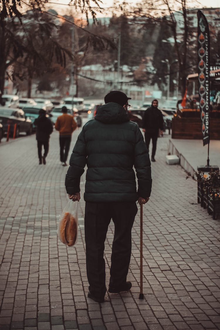 Back View Of A Man Walking With A Cane