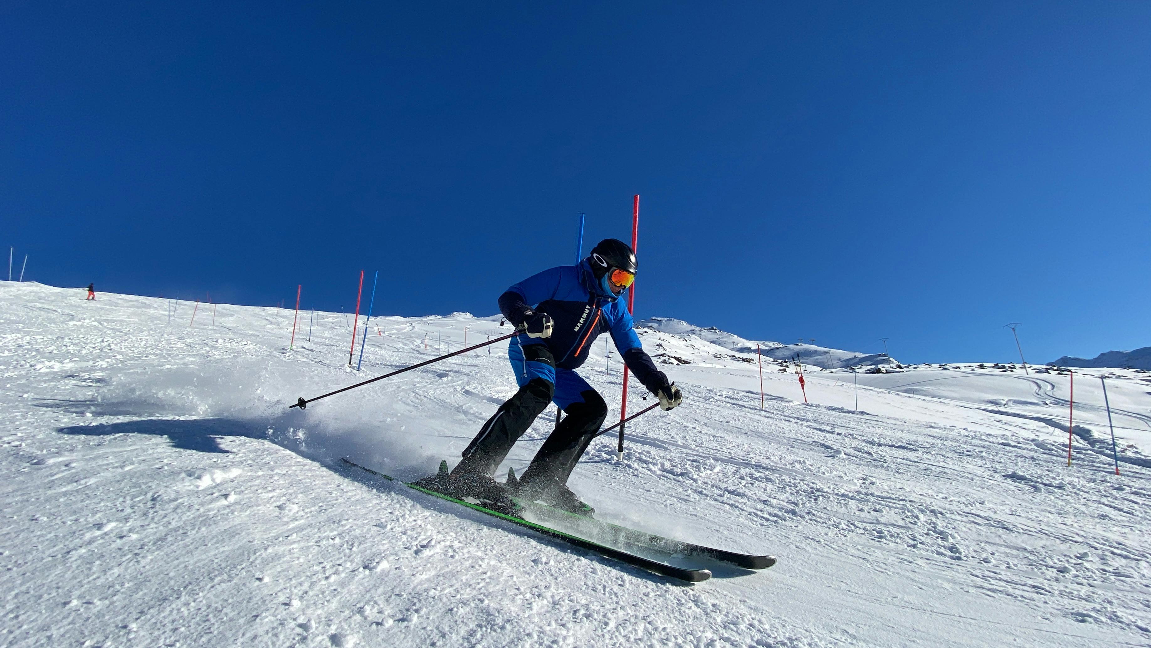 Prescription Goggle Inserts - A dynamic skier races down a snow-covered slope in Les Belleville under a clear blue sky.