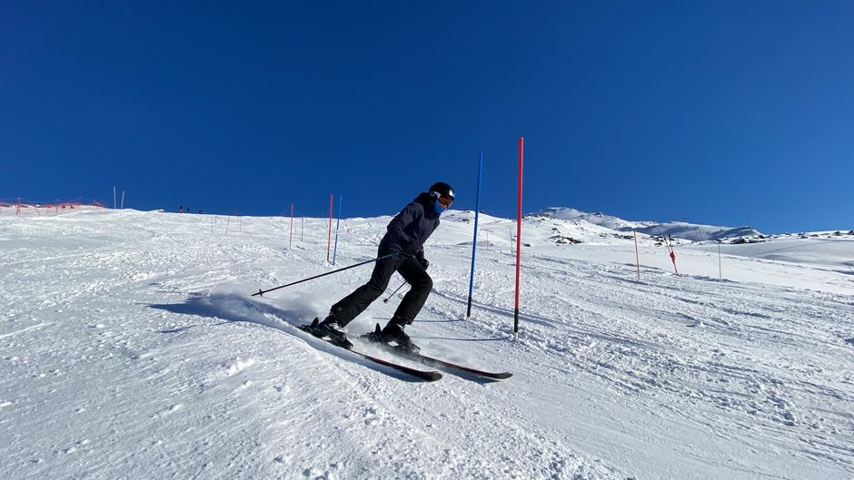 Skier skillfully navigating slalom course in snowy Les Belleville on a bright winter day.