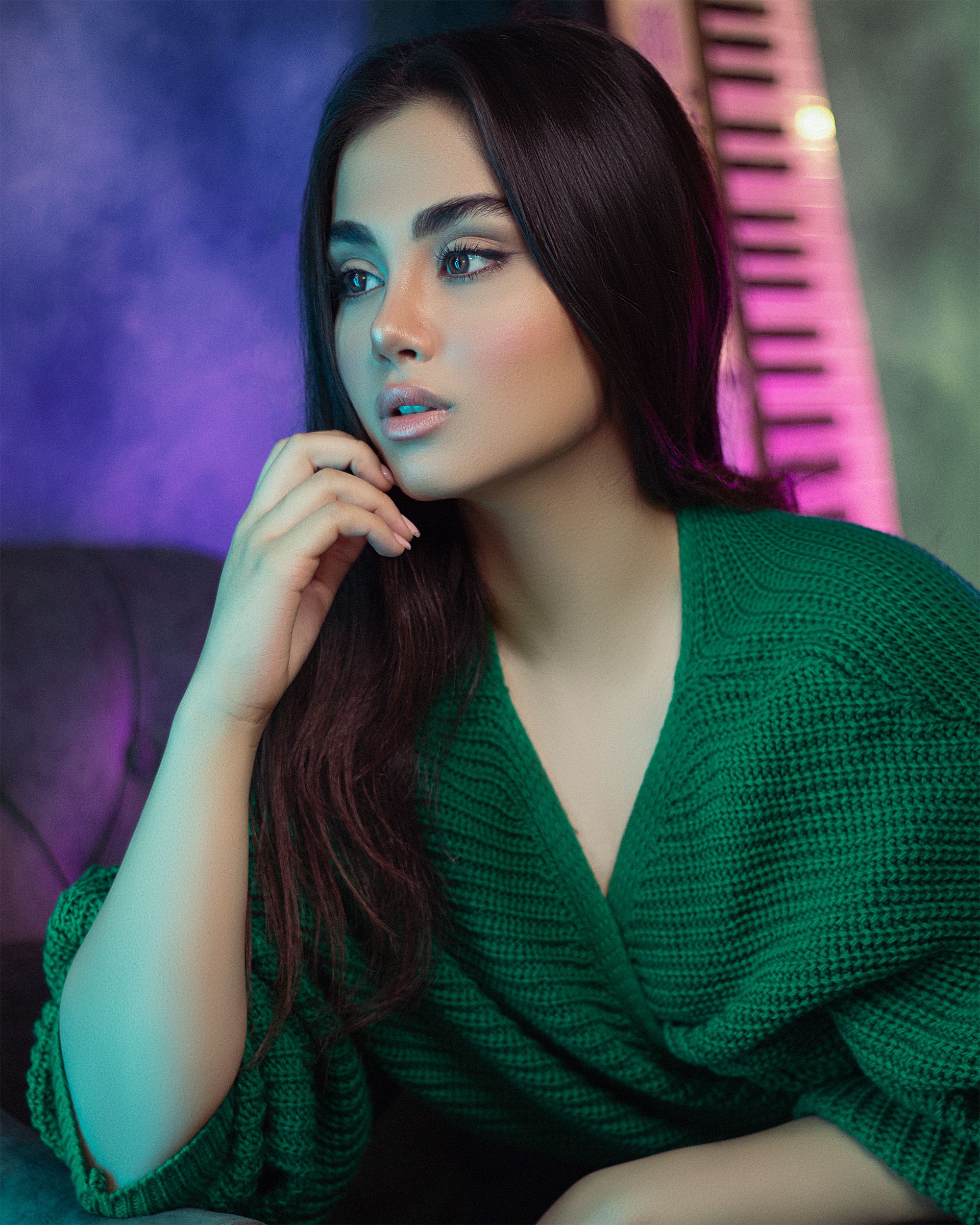 Stylish portrait of a woman in a green sweater posing indoors, with vibrant colors.
