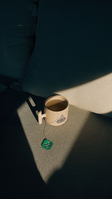 A ceramic mug with tea on a sofa, capturing light and shadow in a minimalist style.