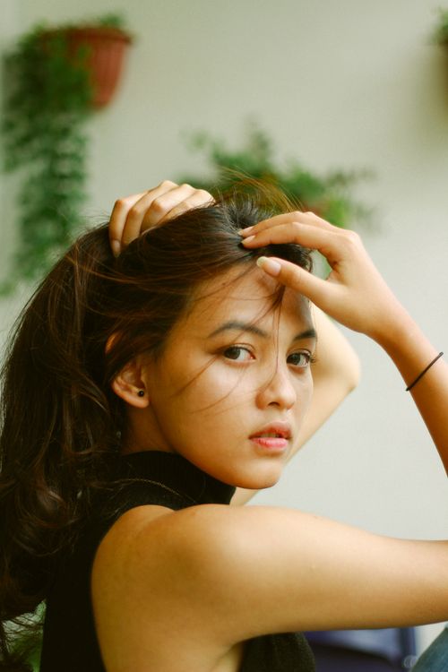 Free Elegant portrait of a young woman outdoors, touching her hair, creating a serene and natural vibe. Stock Photo