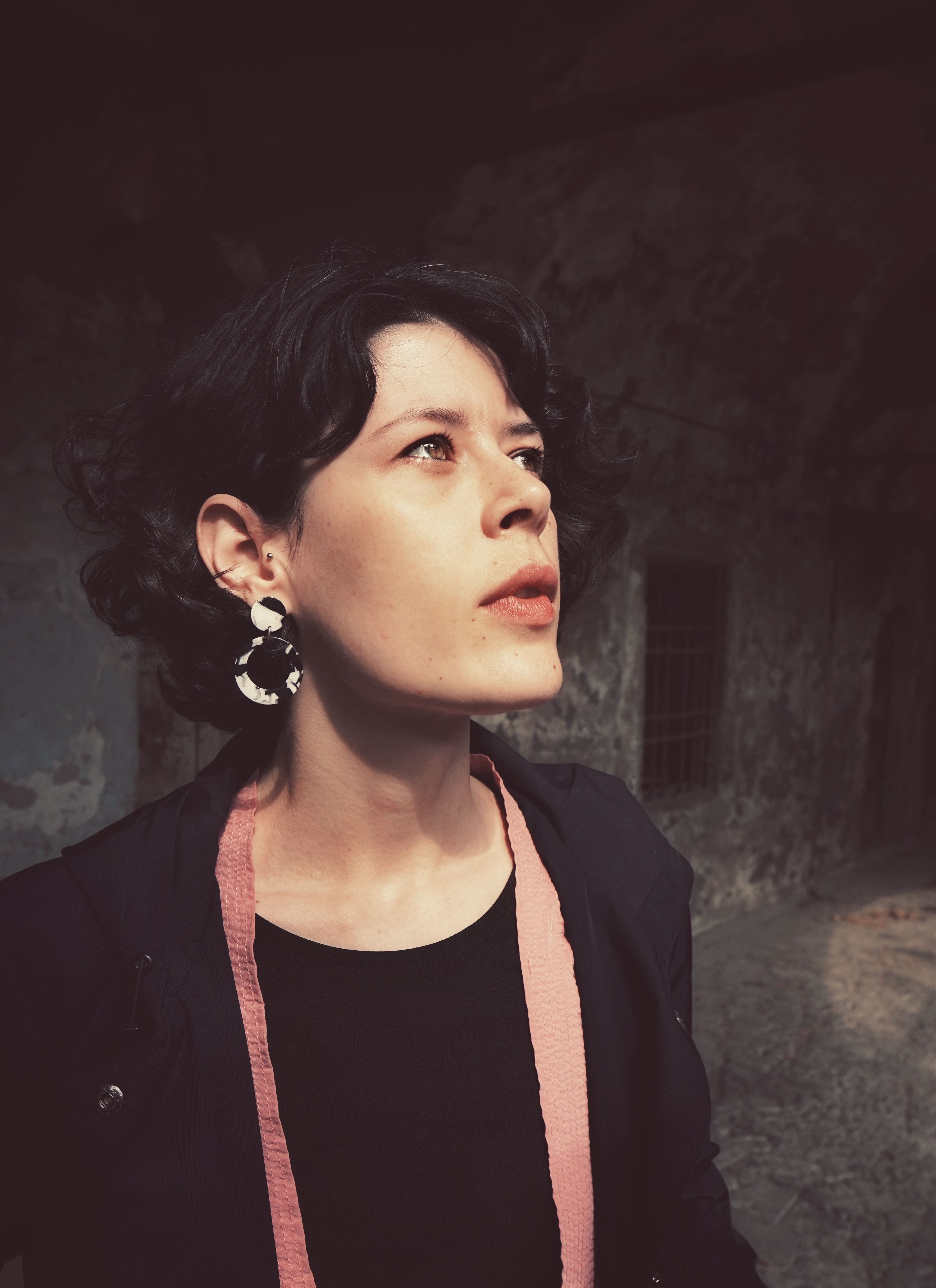 Dramatic portrait of a woman in dim lighting, creating a thoughtful and moody atmosphere.
