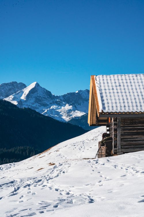 Free A rustic wooden shed in a snowy Bavarian landscape with clear winter skies and majestic mountains. Stock Photo