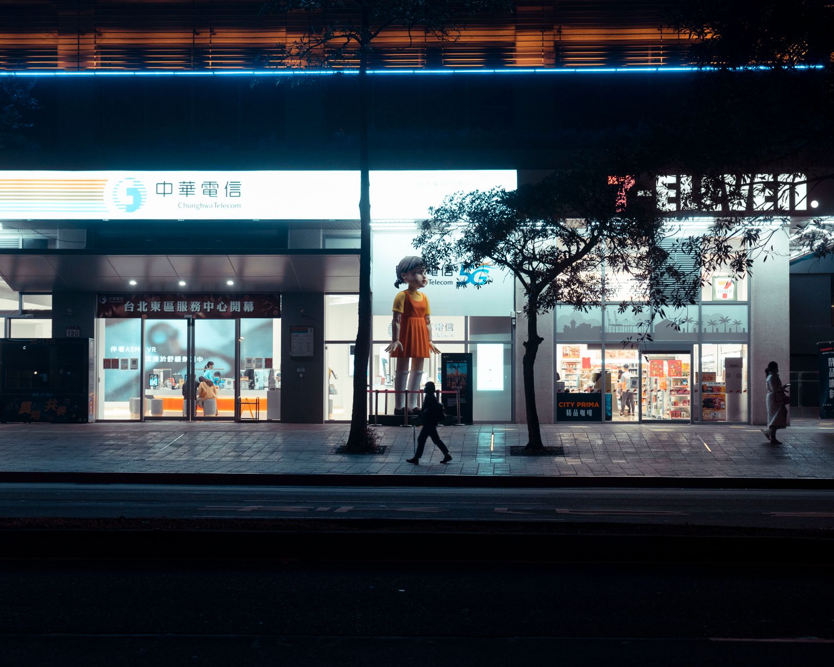 Vibrant city scene at night showcasing neon-lit shops and pedestrians on the sidewalk.