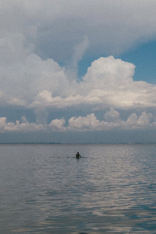 Person in the Sea Under Beautiful Clouds in Sky