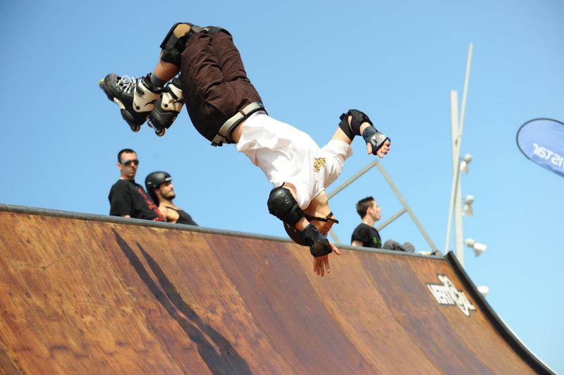 Roller skating stunt at a sunlit skatepark