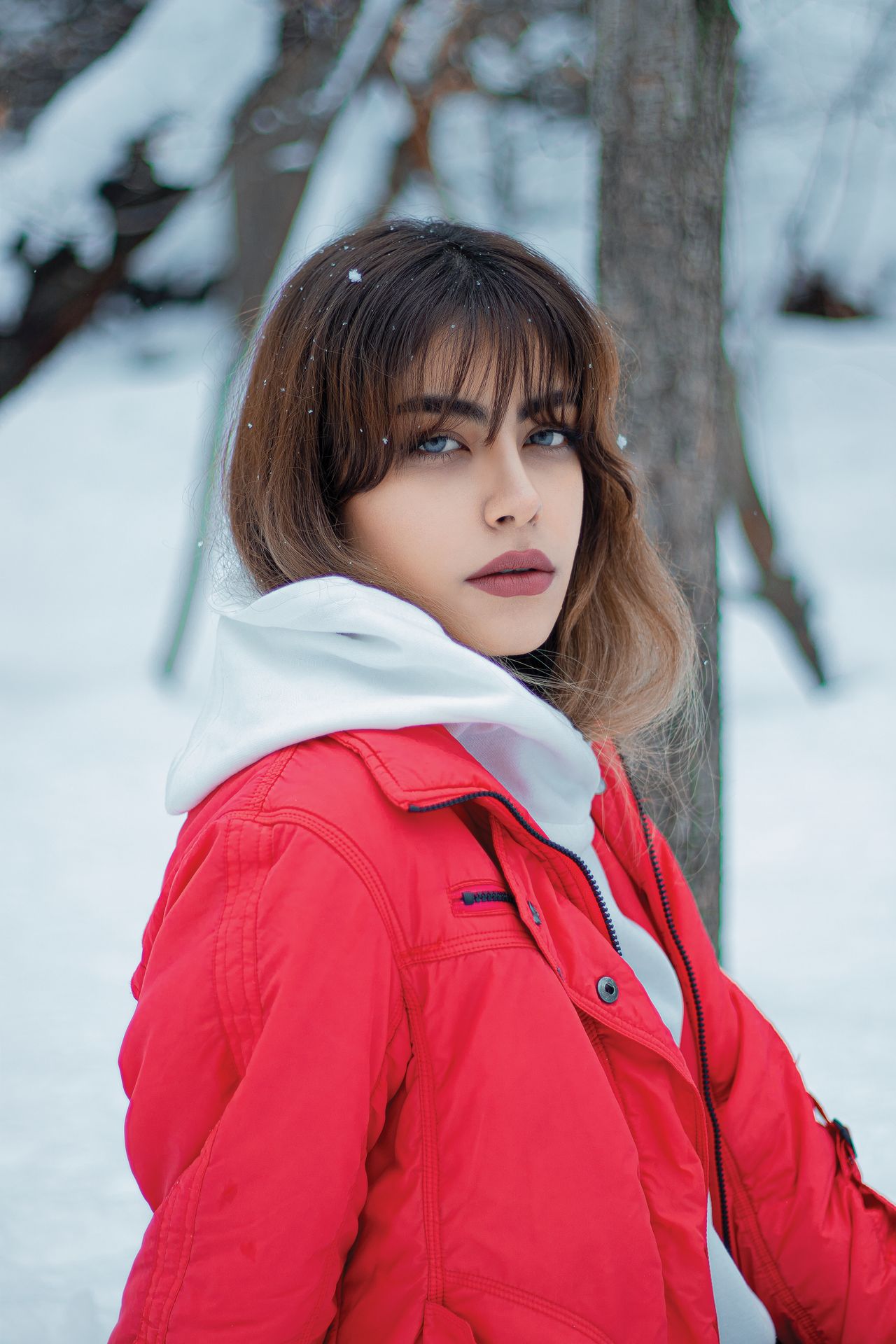 Woman in a red winter jacket and white hoodie in the snow