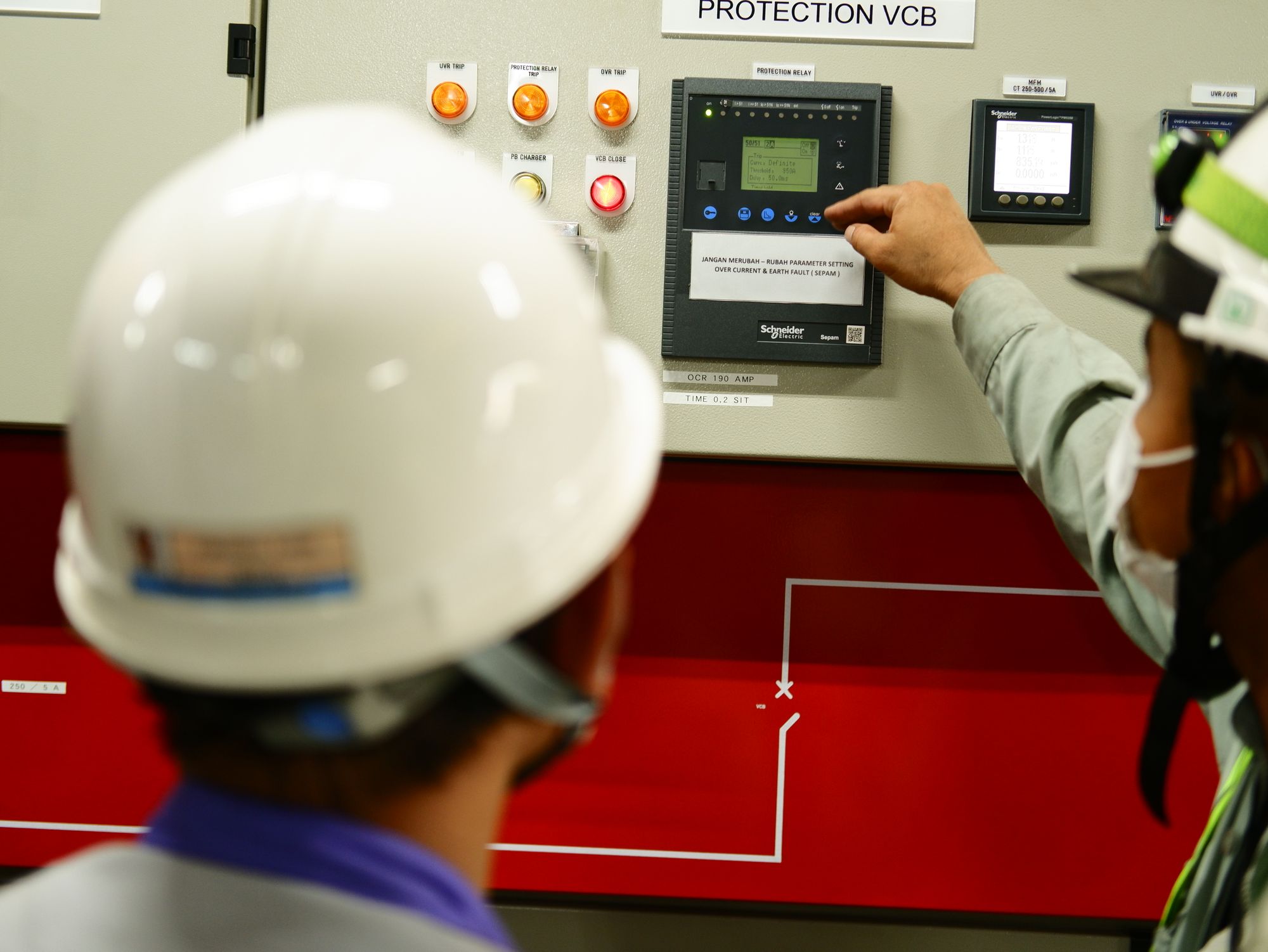 Sala de control eléctrica con varios operadores frente a pantallas que muestran curvas de generación y demanda
