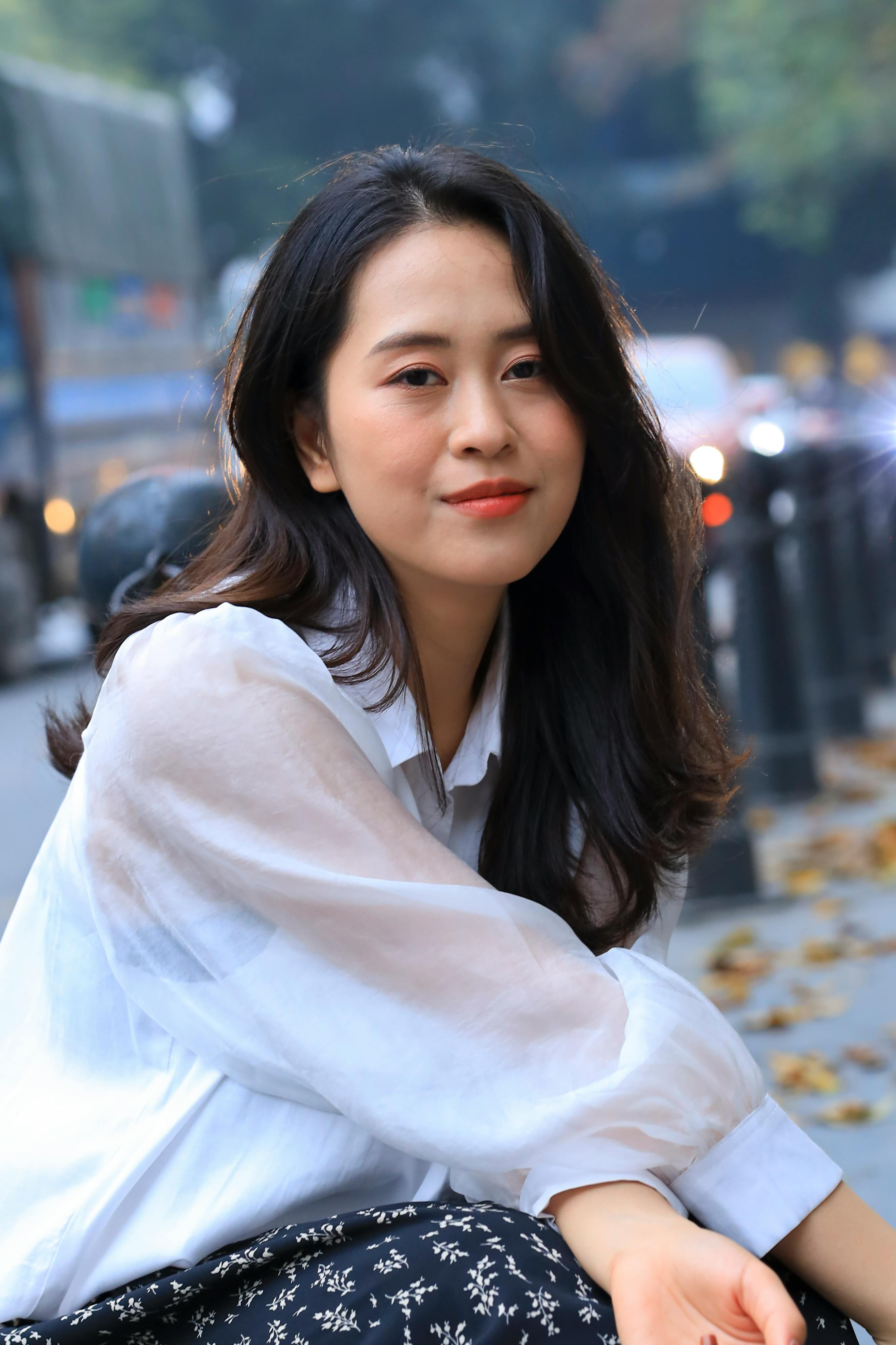 Asian woman in white blouse with a blurred city background and depth of field.