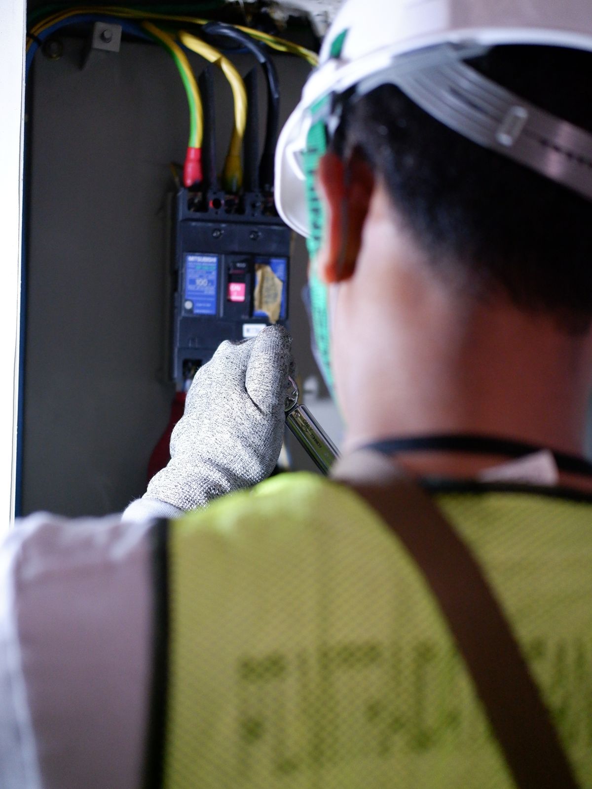 Electrician wearing gloves working safely on a circuit breaker panel