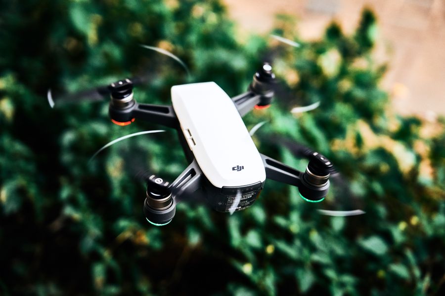A DJI style quadcopter drone in flight over foliage