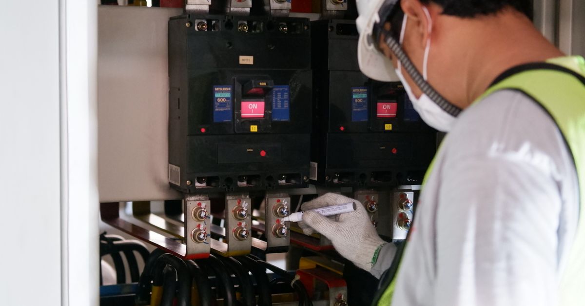 Electricista trabajando en un cuadro de distribución eléctrico