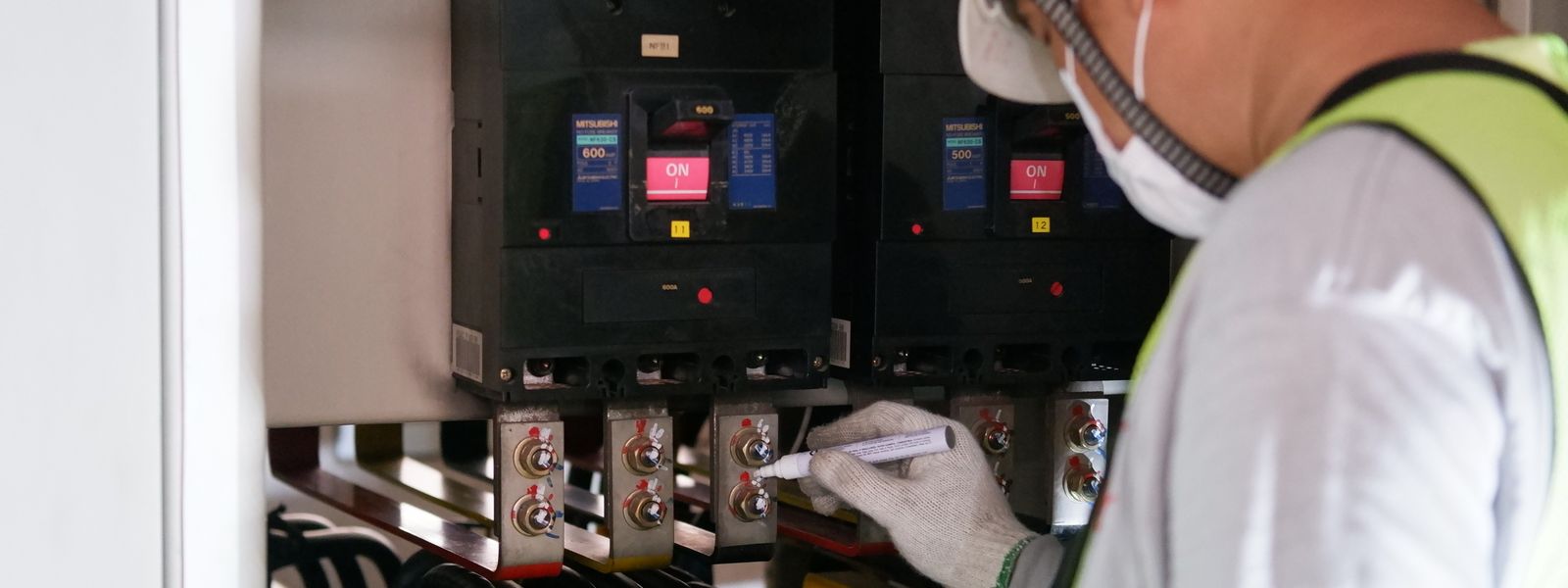 Technician inspecting electrical panels in an industrial facility
