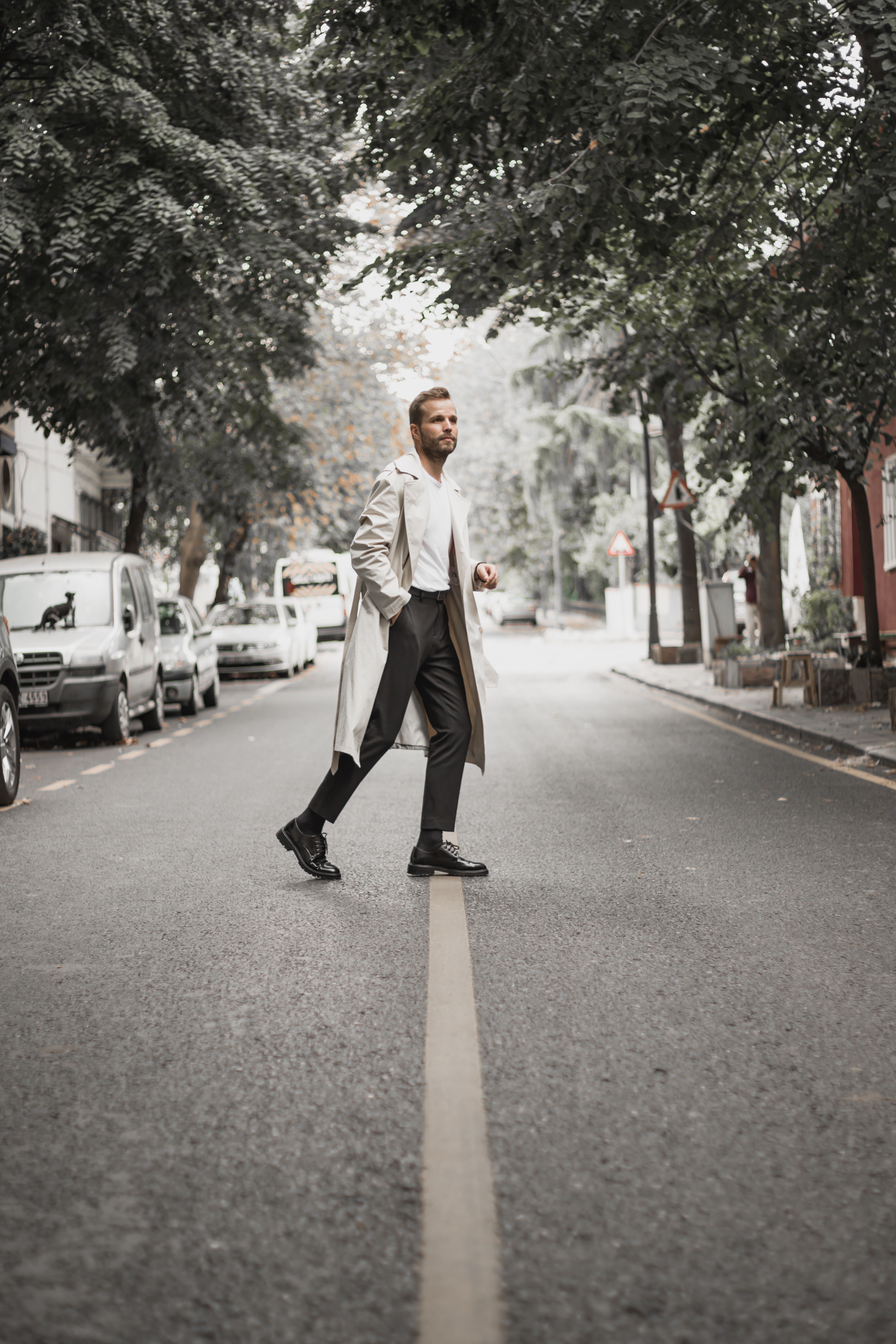 Man in coat walks across a quiet urban street in Istanbul, embodying modern city life.