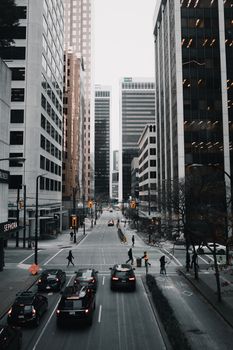 Urban street view of Vancouver's downtown with high-rise buildings and city traffic under overcast skies.