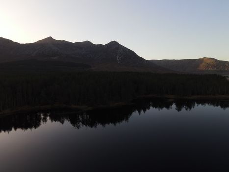 Drone view of tranquil landscape with mountain and lake reflections in Connemara, Ireland.